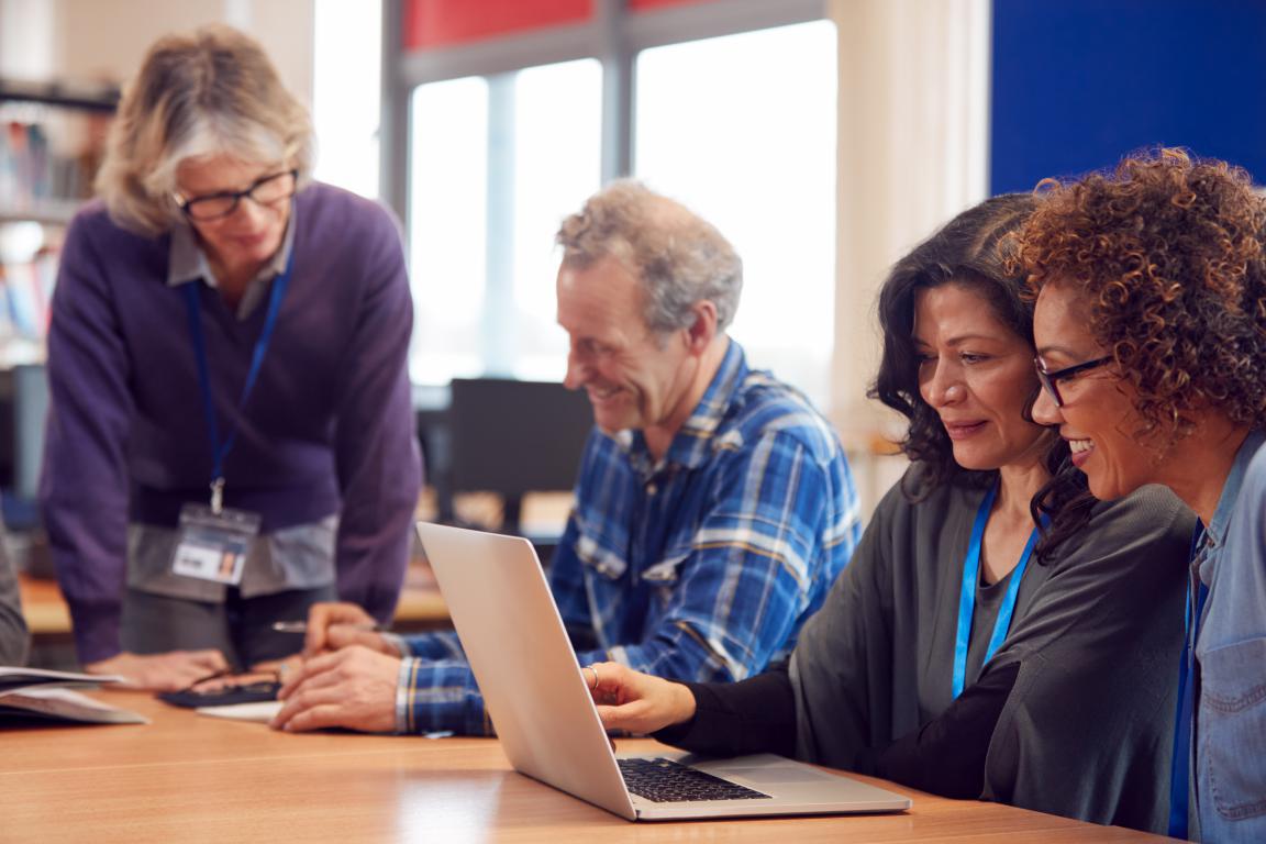  A group of people are sitting together and looking at a laptop, appearing to be in a meeting or discussion