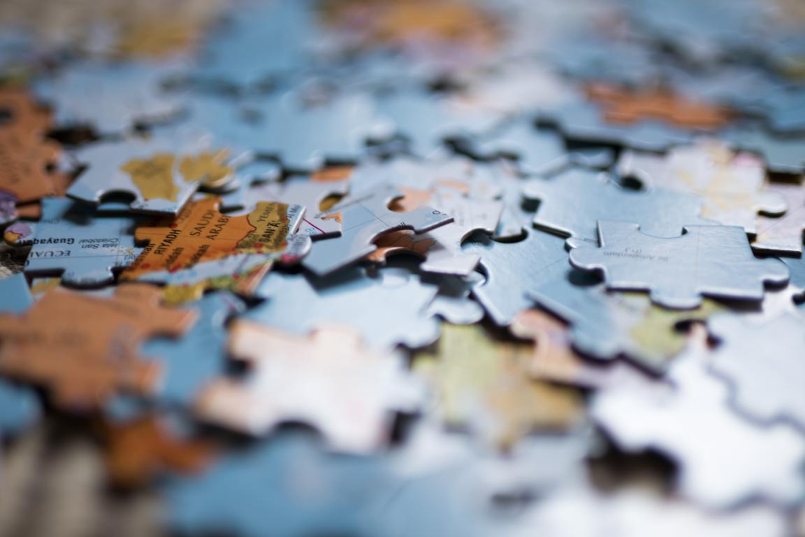 A close-up shot of scattered jigsaw puzzle pieces, which form a map of the world, representing a calming, low-stimulation activity.