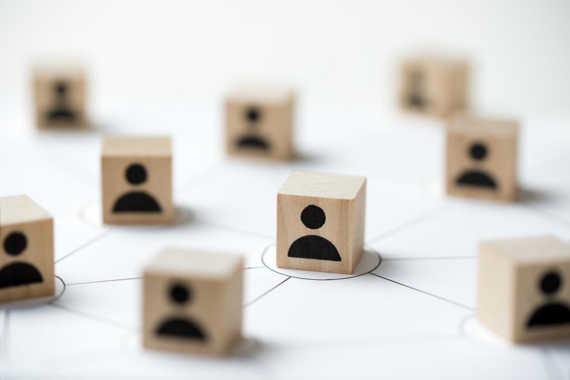 Wooden blocks with person icons are connected by drawn lines to illustrate a professional network.
