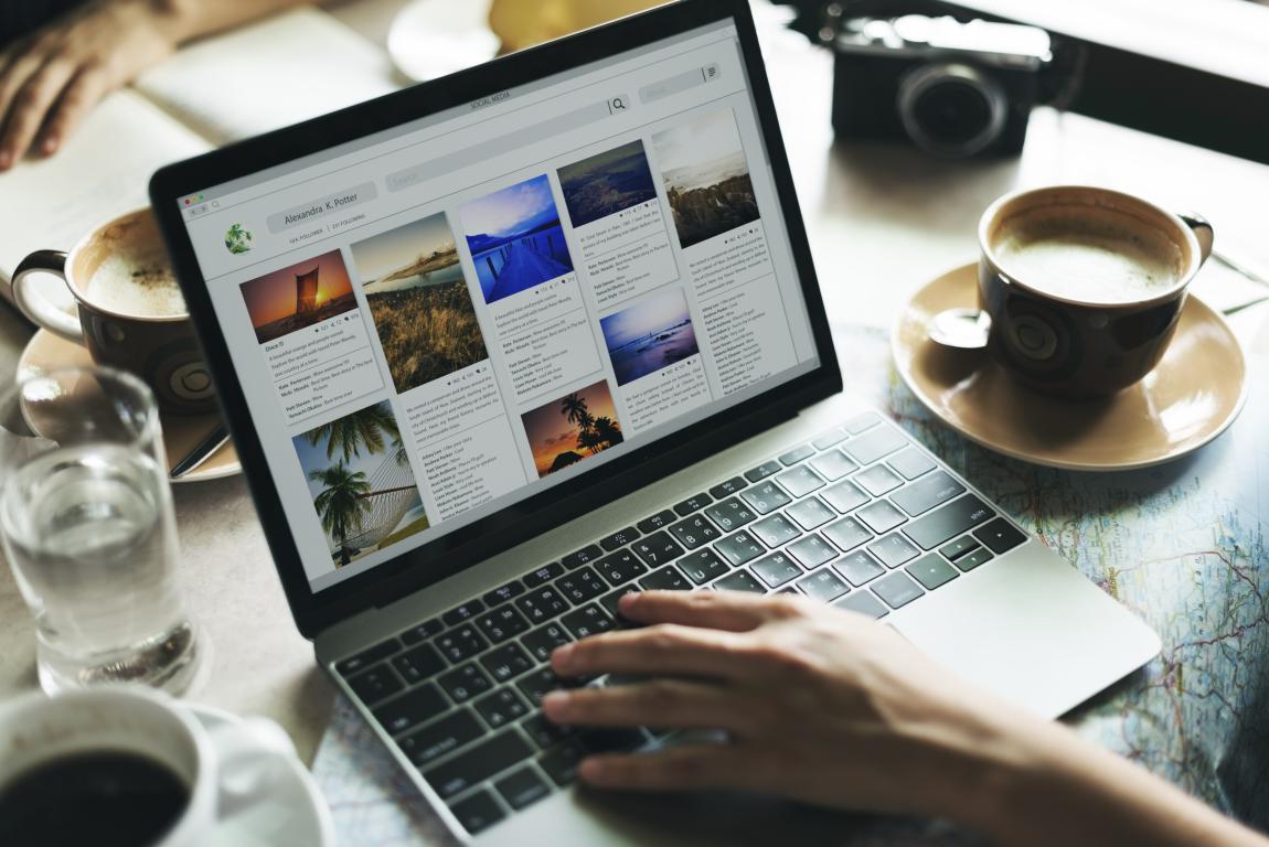  A person browsing a professional online photo portfolio on a laptop, with coffee cups on the desk.