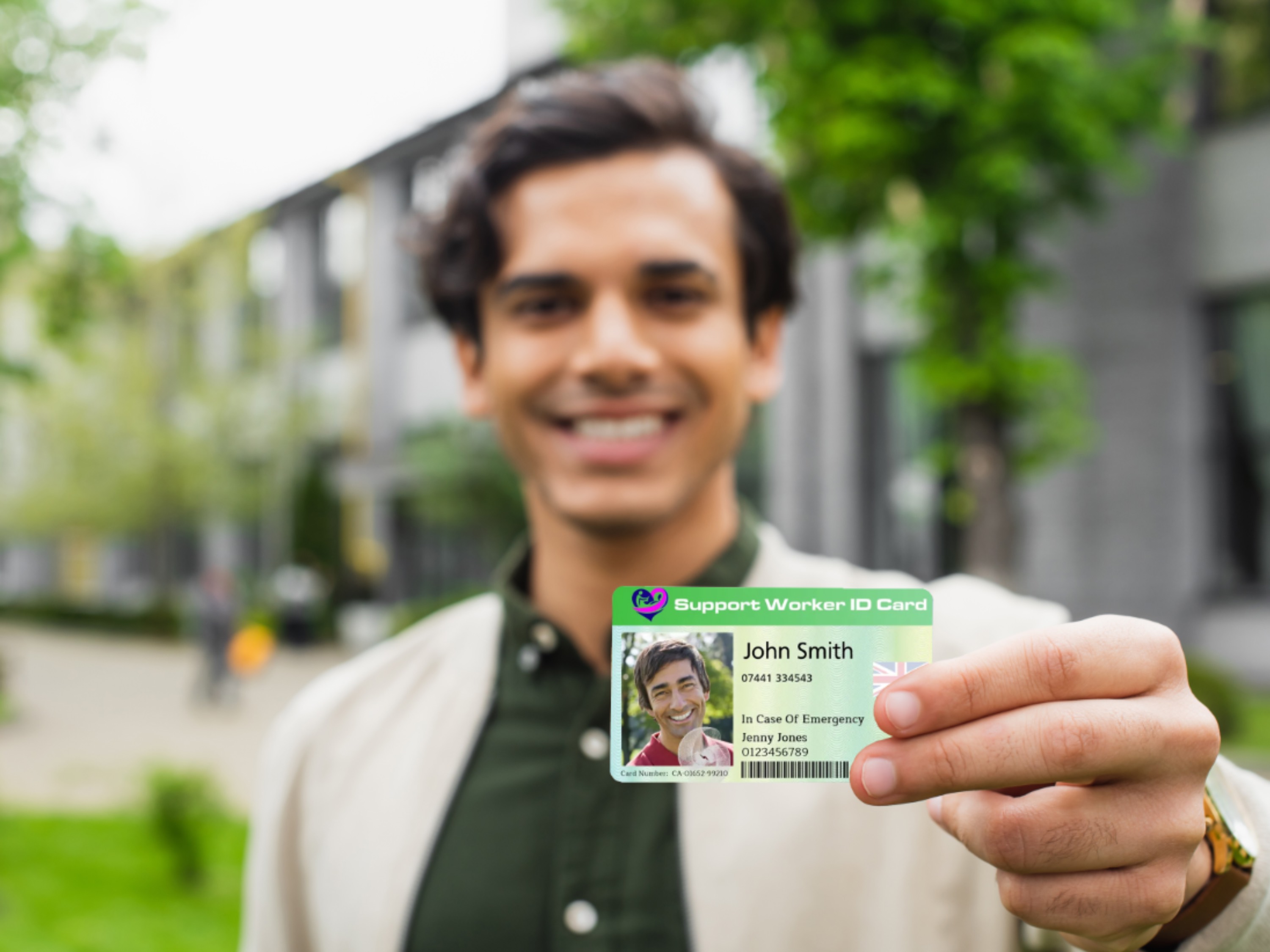 A man holds up his professional Support Worker ID card, clearly showing his photo, name, and contact details for verification.