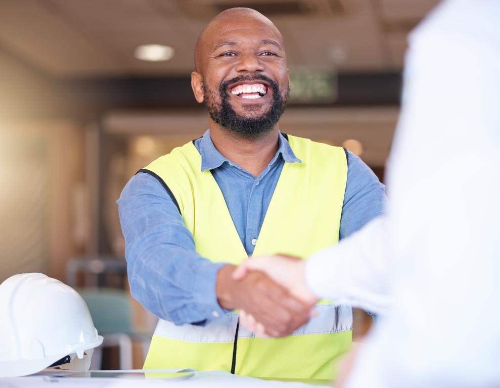  A smiling contractor in a safety vest shakes hands with a client, showing the trust built by a professional small business.