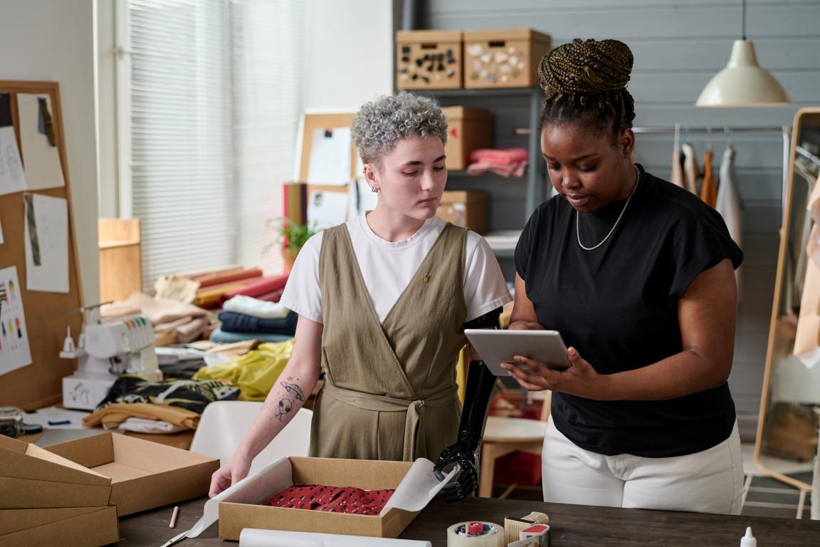 Team members in a small e-commerce business work together, using a tablet to review an order before it's packed for shipping.