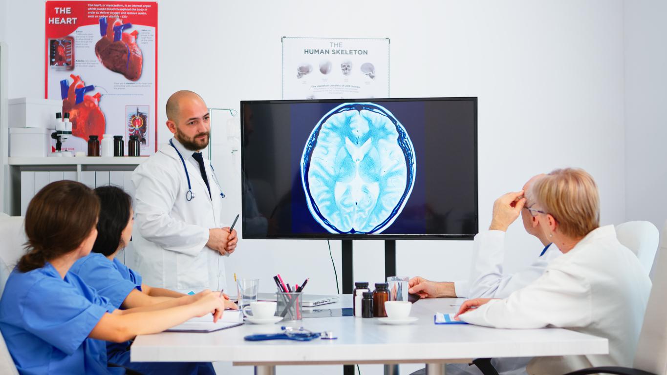  A doctor discusses a brain MRI scan with colleagues, highlighting the importance of diagnostics for neurological implant candidates.