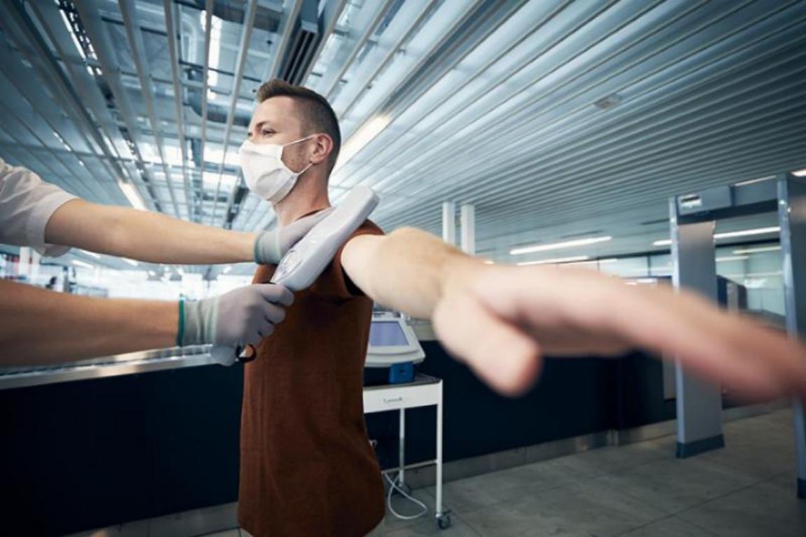 A man being scanned with a handheld metal detector by a security officer at an airport, a common situation for those with medical implants.