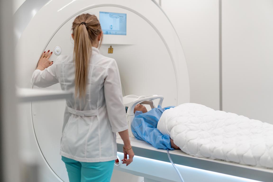 A radiographer preparing a patient for their scan, operating the MRI machine to begin the imaging process safely.