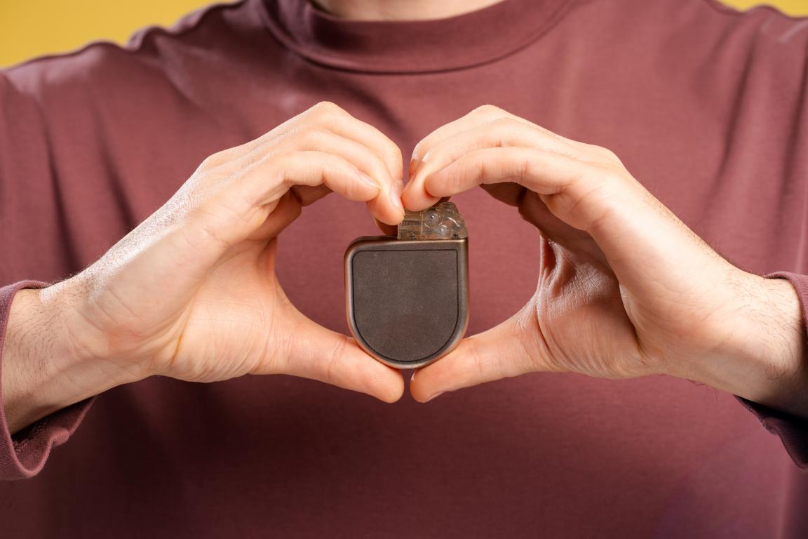  A person making a heart shape with their hands around their pacemaker, illustrating the importance of protecting the device during airport security.