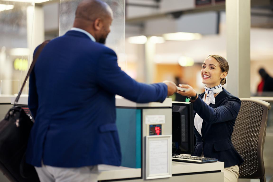  A man calmly handing a medical ID card to a friendly UK airport agent to explain his metal implant before going through security.