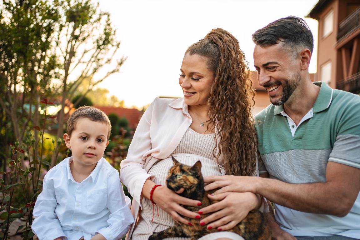 A happy family with their young son holding their tortoiseshell cat, showing the importance of protecting a beloved pet with cat insurance.