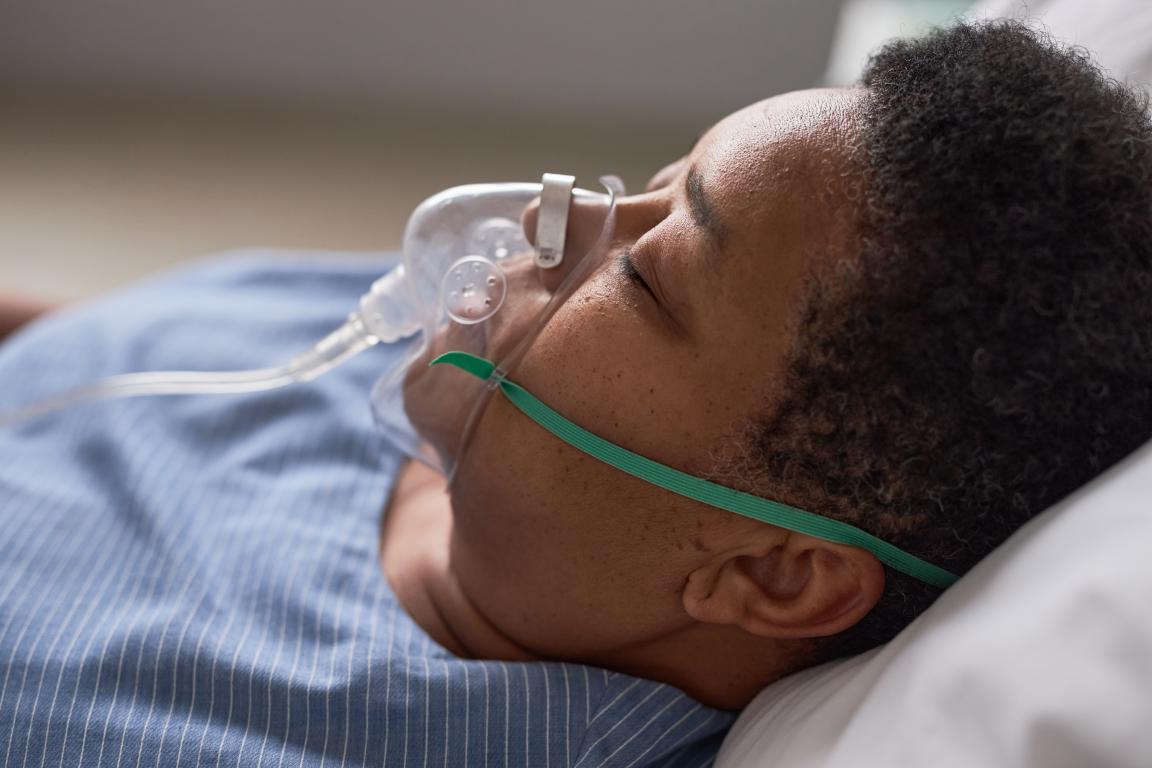  Close-up of a person lying down with an oxygen mask covering their nose and mouth.