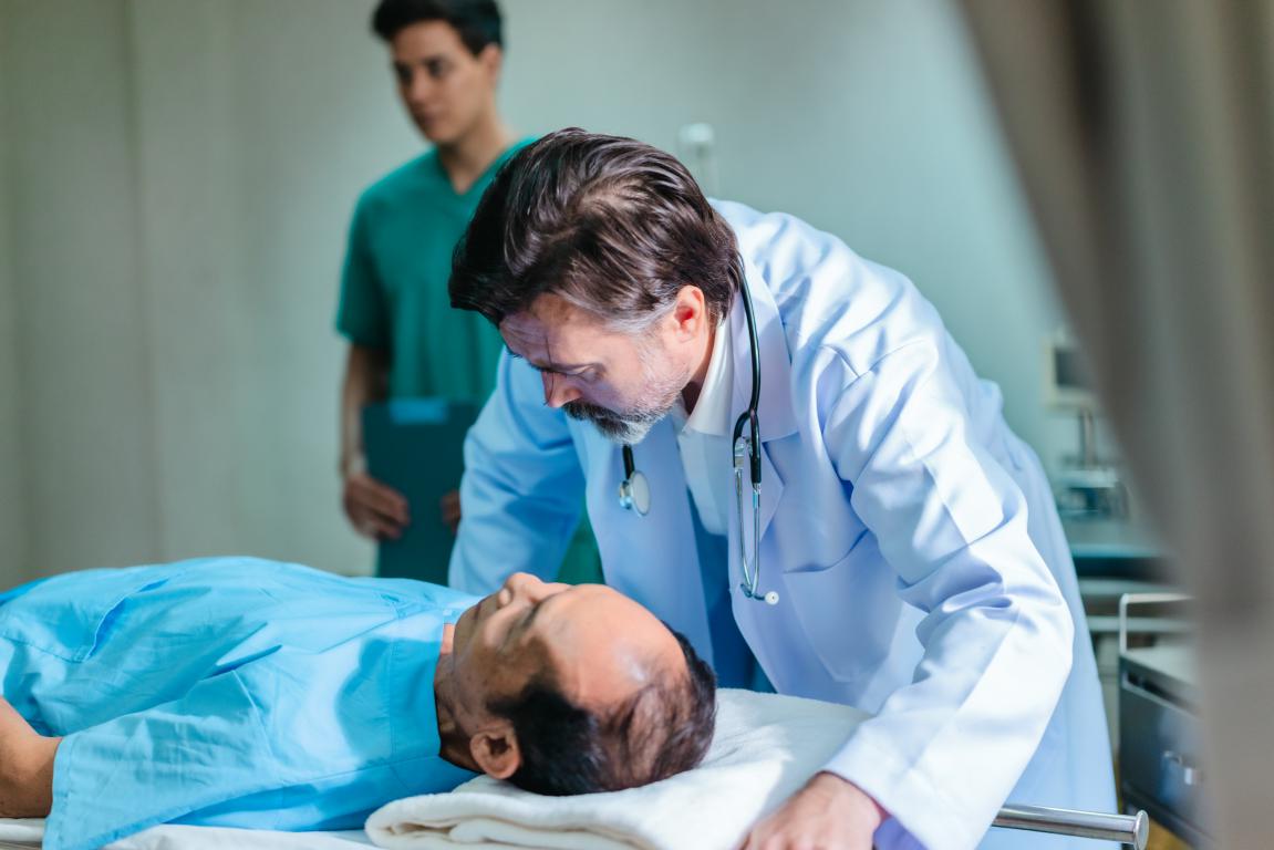  A doctor is examining a patient on a hospital bed, potentially during a consultation about sleep apnea or sleep study results.