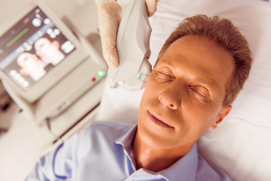 A man with closed eyes undergoes a medical procedure, possibly related to monitoring or treatment for sleep apnea, such as a sleep study.