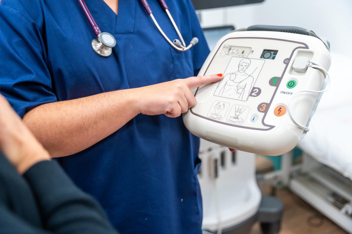 A medical professional points to the diagrams on a portable defibrillator, illustrating how the device works, which can be reassuring for those learning about ICDs.