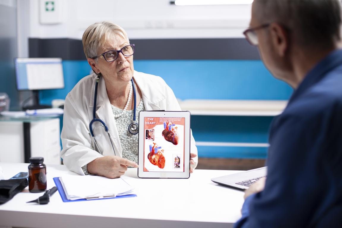 A doctor explains how an ICD works by showing heart rhythms on a tablet to a patient.