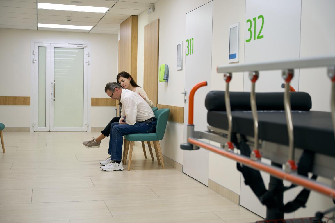  A couple sits together in a hospital corridor, reflecting the shared experience of waiting.