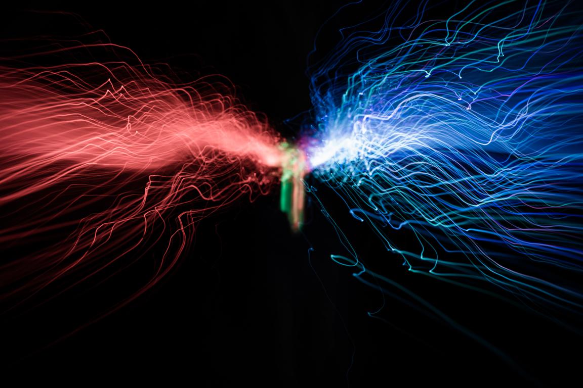 An abstract image showing streams of red and blue light converging, representing electrical currents or energy fields.