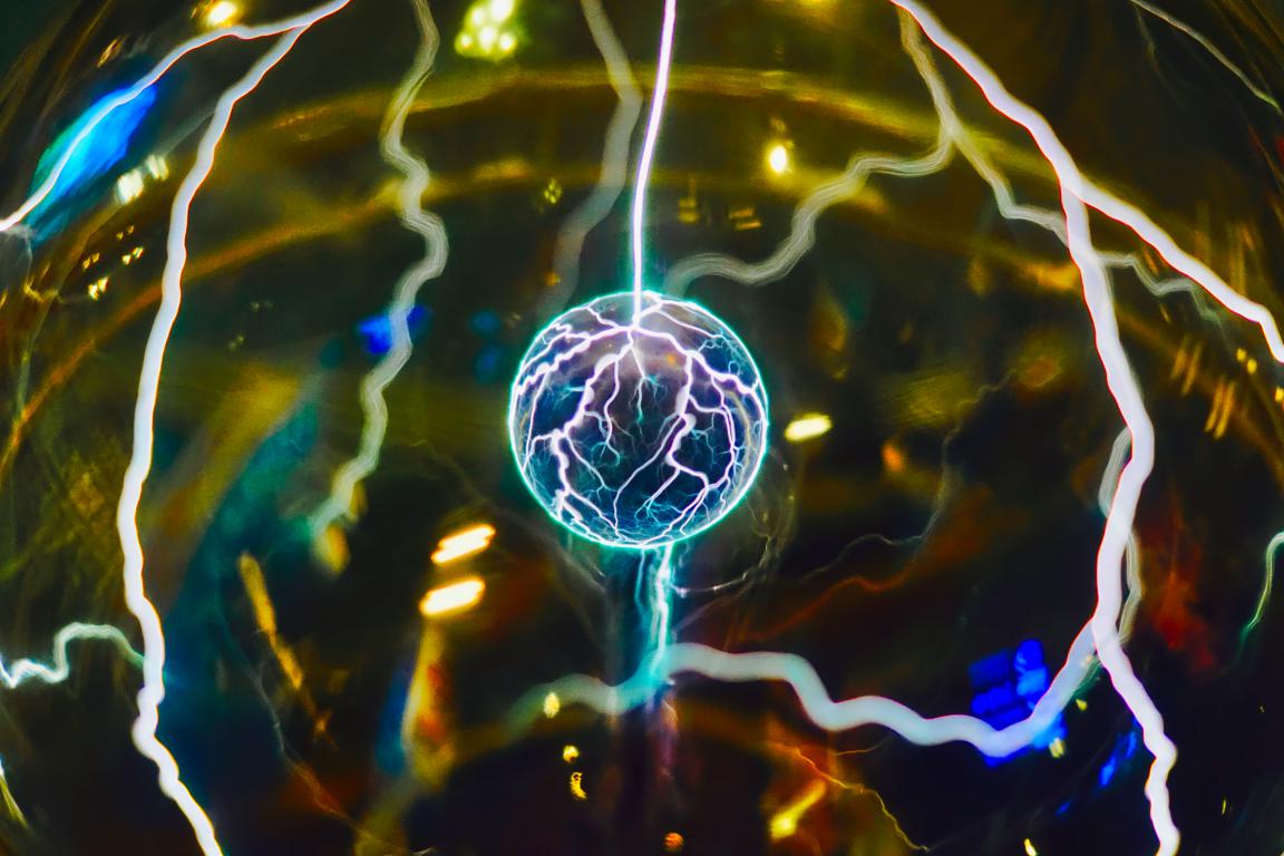 A plasma ball showing bright electrical discharges and filaments of light reaching towards its centre.