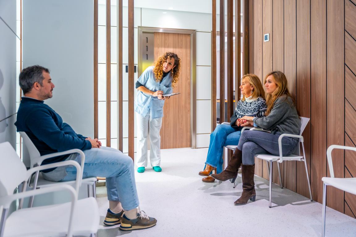  A nurse speaking with patients in a brightly lit hospital waiting room