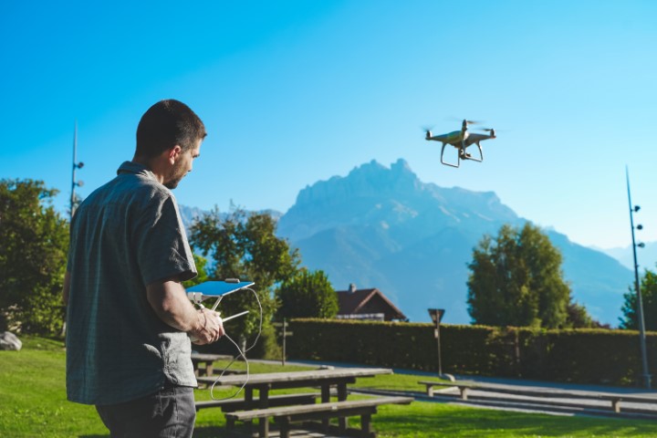 Man flying a drone on a sunny day near mountains