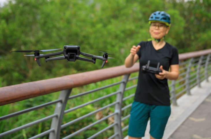 Woman flying a drone on a bridge