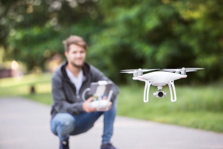 Man kneeling down whilst flying a drone in a park