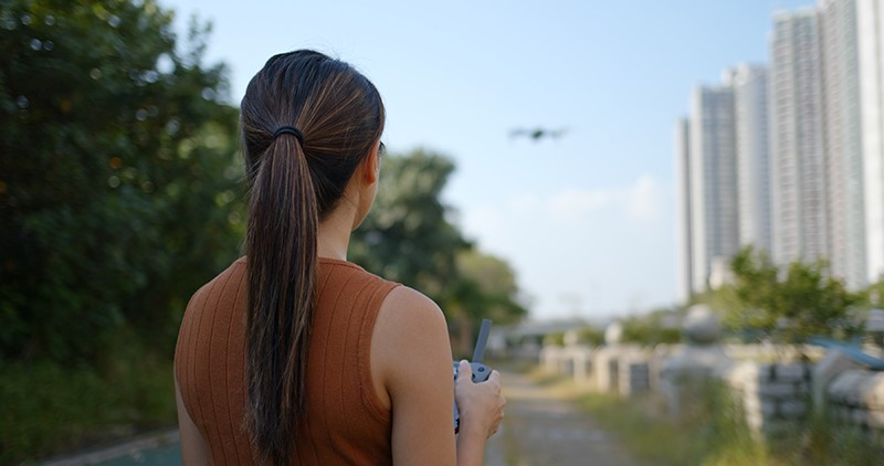 woman flying a drone in a city