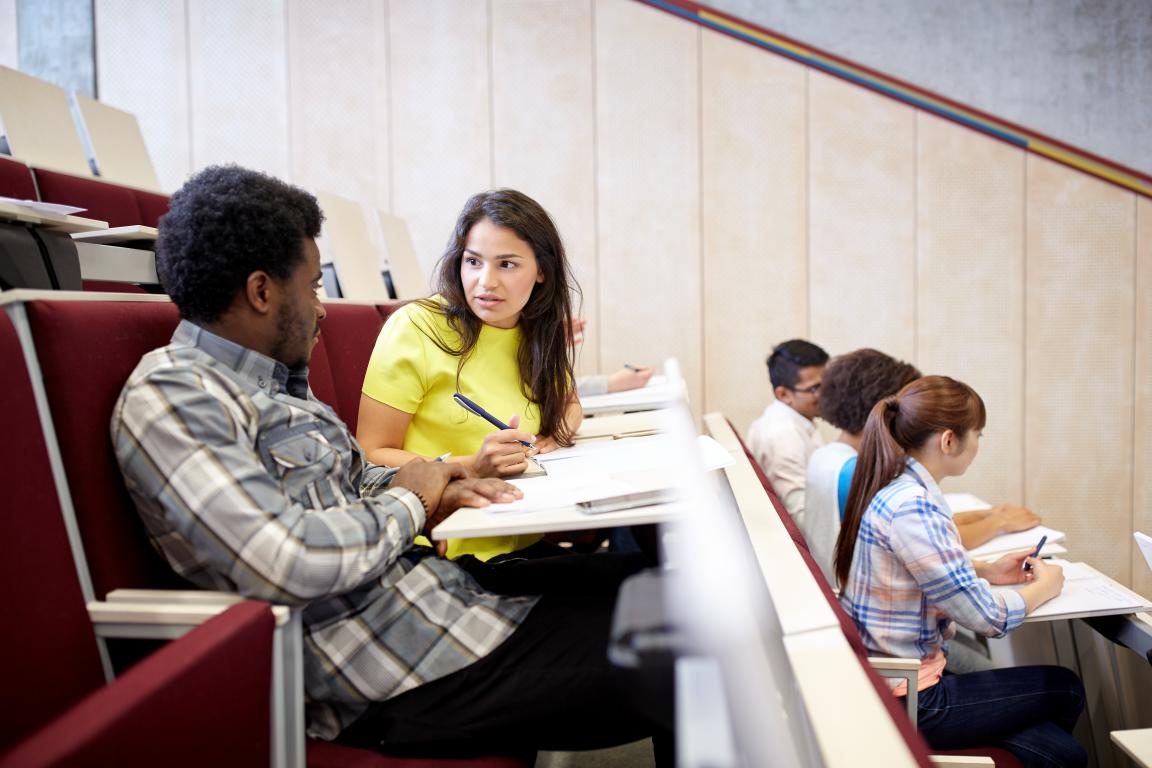 Students talking in a university lecture theatre, relevant to attendance tracking.