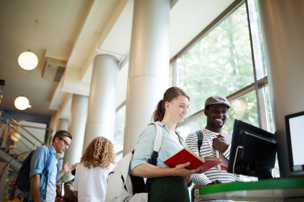 Students checking their account balance or printing status at a university library computer terminal.