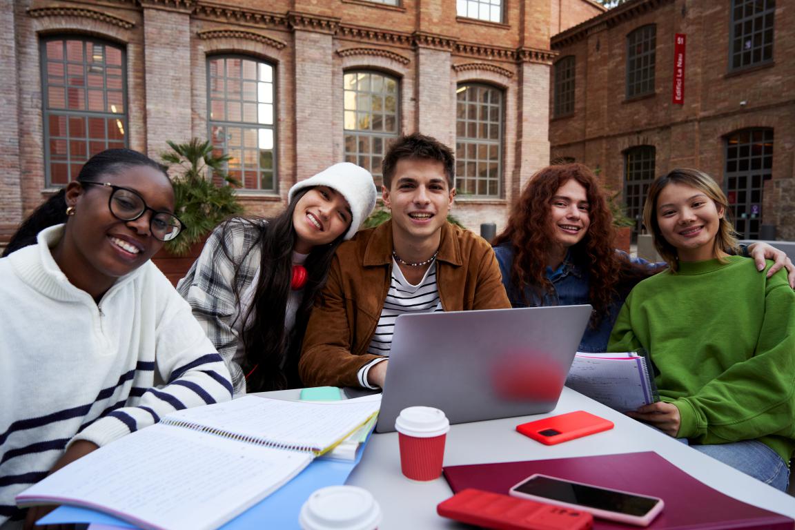 Happy, diverse group of students studying outdoors on campus.