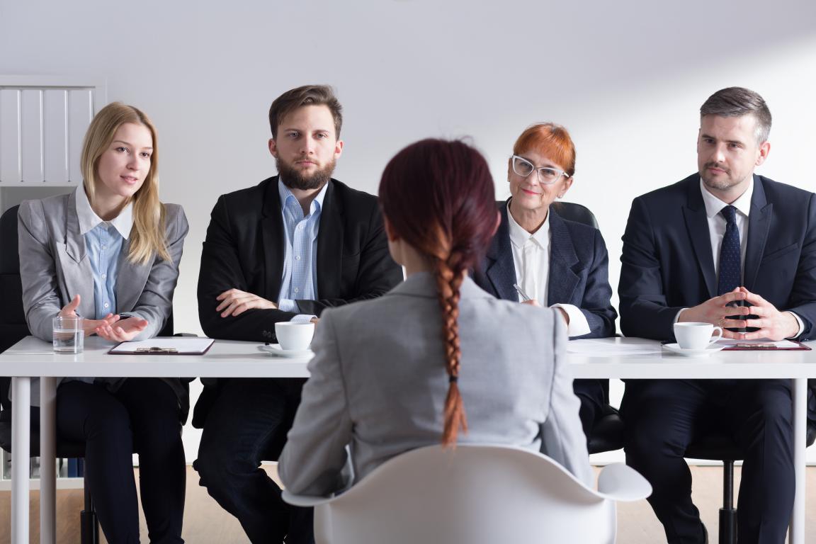 Candidate sitting confidently in front of a panel of interviewers, ready to talk about the training and certifications listed on her portable ID card