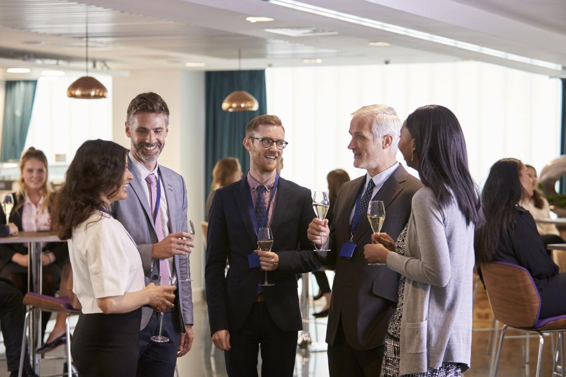 A happy delegate at a networking coffee break, wearing her training ID badge on a lanyard – the perfect moment for someone to ask “Where did you do your course?”