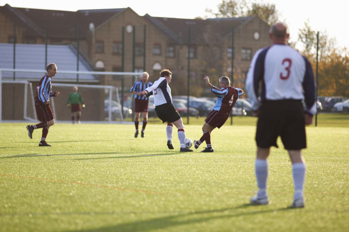 Adult players tackling in a Sunday league football game