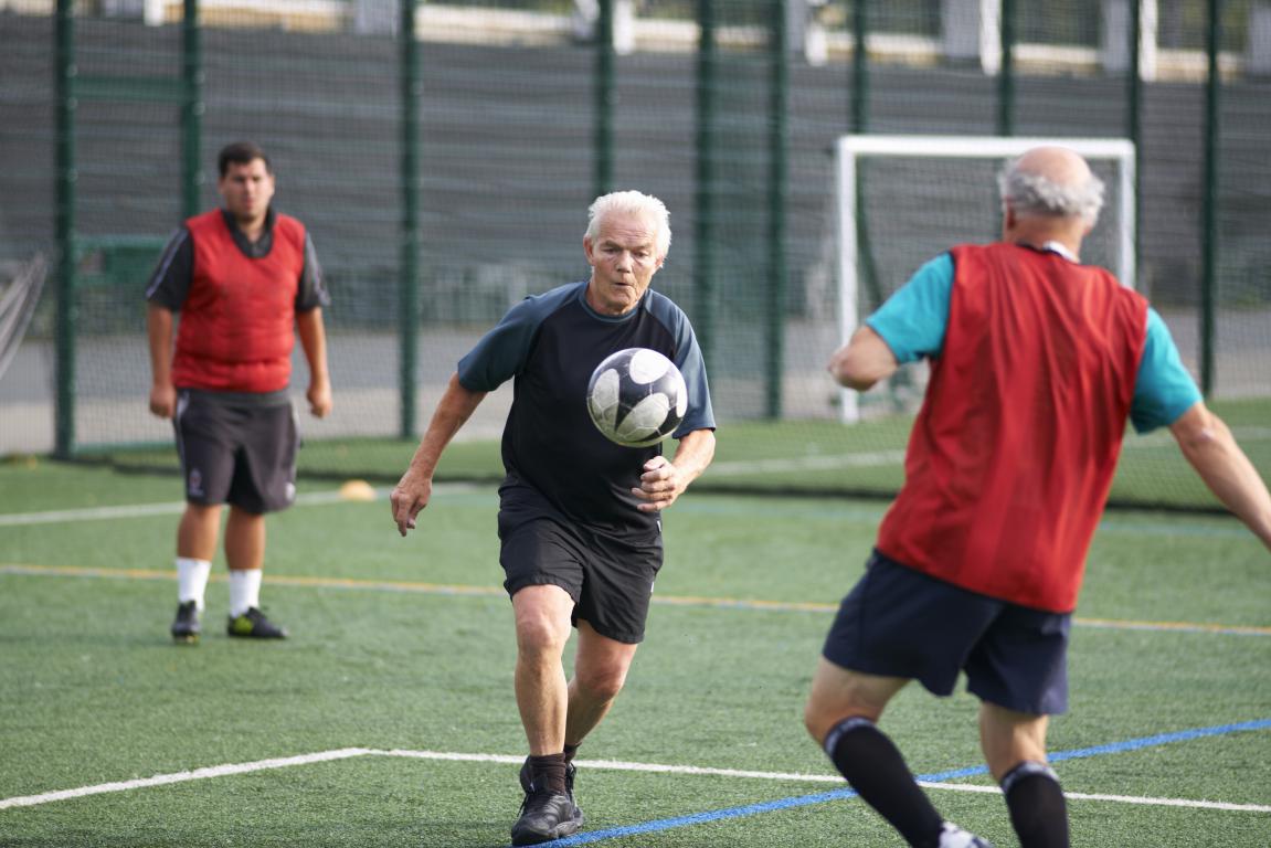 A group plays a match on a grass pitch.